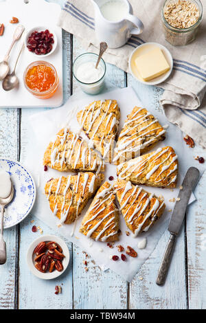 Scones con l'avena, il mirtillo palustre e noci pecan su sfondo di legno. Vista dall'alto. Foto Stock