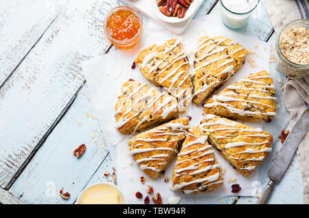 Scones con l'avena, il mirtillo palustre e noci pecan su sfondo di legno. Vista dall'alto. Copia dello spazio. Foto Stock