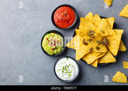 Nachos chips su una piastra con salse, varietà dip. Grigio pietra dello sfondo. Vista dall'alto. Copia dello spazio. Foto Stock