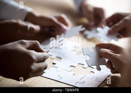 Close up i membri del team e multirazziale assemblaggio puzzle bianco Foto Stock