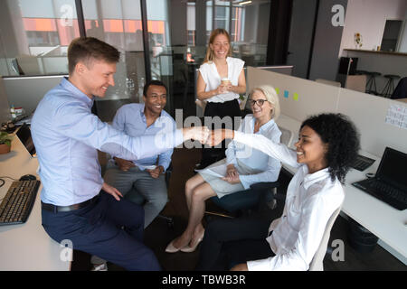 Diversi colleghi fist bumping, celebrando il lavoro di squadra il successo di briefing Foto Stock