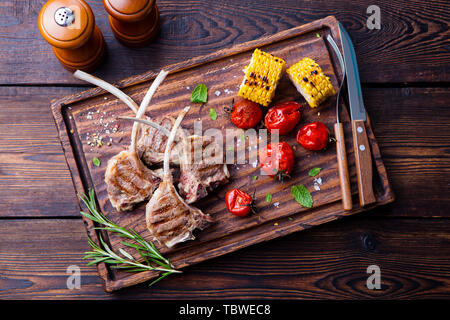 Costolette di agnello grigliate sul tagliere con verdure alla griglia. Vista dall'alto. Foto Stock