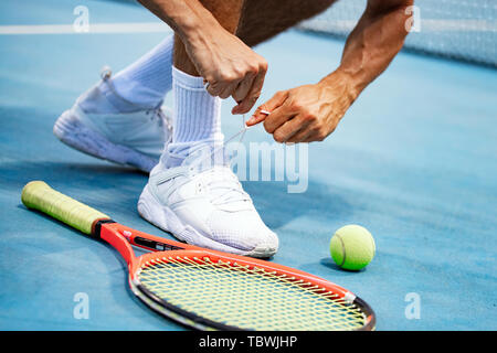 Atleta di Tennis player sta preparando la legatura lacci delle scarpe durante il gioco all'aperto Foto Stock