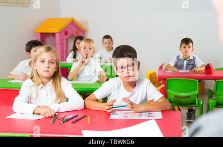 Prospettiva in prima persona di bambini a scrivanie in aula Foto Stock