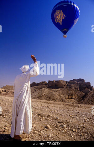 Foto: © Simon Grosset. Volo in mongolfiera sopra la Valle dei Re Luxor Egitto. Un egiziano in abiti tradizionali onde per il palloncino. Archivio: Foto Stock