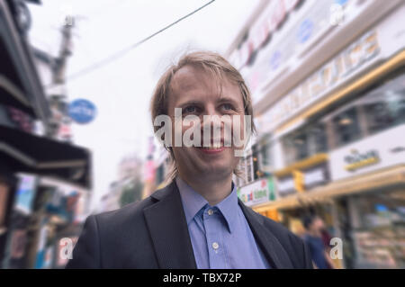 Uomo sorridente a piedi a korean shopping street Foto Stock