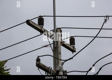 Primo piano linea di elettricità e l'elettricità post all cielo blu sullo sfondo Foto Stock