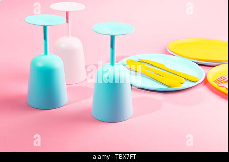 Colore luminoso picnic in plastica utensili. Rosa, giallo, blu nel recipiente. Foto in hard light. Spazio di copia Foto Stock