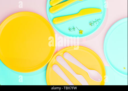 Colore luminoso picnic in plastica utensili. Rosa, giallo, blu nel recipiente. Foto in hard light. Spazio di copia Foto Stock