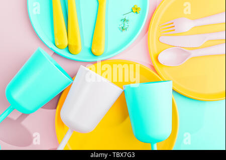 Colore luminoso picnic in plastica utensili. Rosa, giallo, blu nel recipiente. Foto in hard light. Spazio di copia Foto Stock