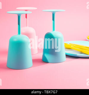 Colore luminoso picnic in plastica utensili. Rosa, giallo, blu nel recipiente. Foto in hard light. Spazio di copia Foto Stock