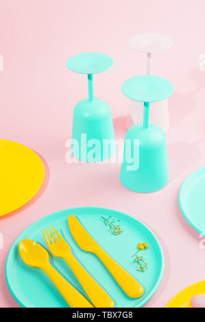 Colore luminoso picnic in plastica utensili. Rosa, giallo, blu nel recipiente. Foto in hard light. Spazio di copia Foto Stock