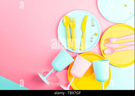 Colore luminoso picnic in plastica utensili. Rosa, giallo, blu nel recipiente. Foto in hard light. Spazio di copia Foto Stock