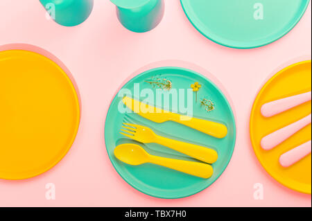 Colore luminoso picnic in plastica utensili. Rosa, giallo, blu nel recipiente. Foto in hard light. Spazio di copia Foto Stock