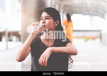 Sport donna è di bere acqua fresca in caldo per esterno Foto Stock