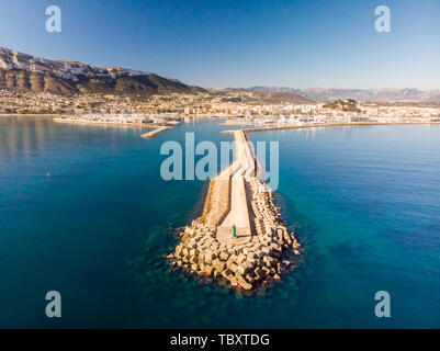 Vista aerea del porto di Denia. Struttura di frangionde ed un faro in primo piano. La città e il Monte Montgo in background. Foto Stock