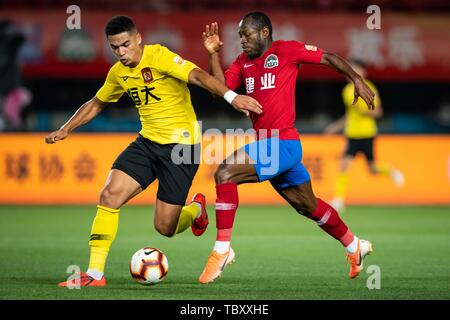 English football player Tyias Browning, sinistra, di Guangzhou Evergrande Taobao passa la palla contro il calcio camerunese player Bassogog Cristiana di Henan Jianye nel loro dodicesimo round corrispondere durante il 2019 Chinese Football Association Super League (CSL) nella Città di Zhengzhou, centrale cinese della provincia di Henan, 2 giugno 2019. Guangzhou Evergrande Taobao sconfitto Henan Jianye 5-2. Foto Stock