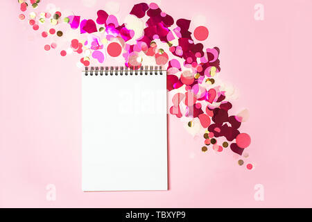 Decorazioni in vacanza con i notebook su rosa pastello con sfondo rosso rosa bianco e oro coriandoli. Foto Stock