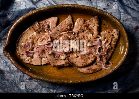 Angolo di alta vista higado encebollado, una ricetta spagnola di fegato di vacca simile a fegato e cipolle, servita in un marrone casseruola di terracotta Foto Stock