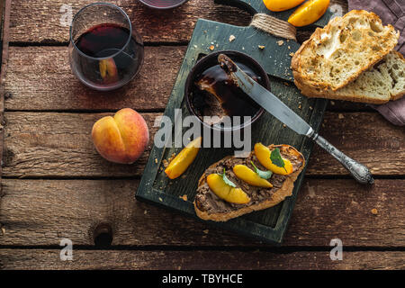 Paté di fegato con griiled pane e pesche, di stile rustico. Foto Stock