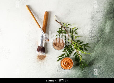 Ciotole con argilla di cosmetici e di spazzole su sfondo chiaro Foto Stock