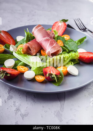 Deliziosa insalata con verdi, fragole, bresaola, grumi e mozzarella. Gustosi e sani. Insalata di italiano. Close up Foto Stock