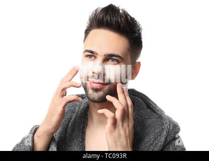 Uomo bello con maschera di argilla sul suo volto contro uno sfondo bianco Foto Stock