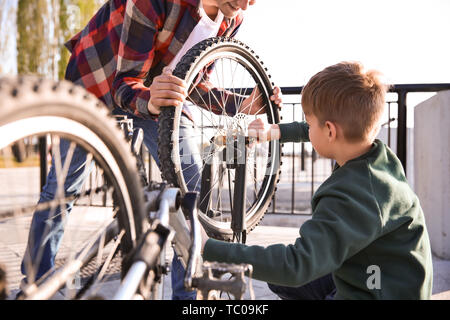 Padre e figlio riparazione bicicletta all'aperto Foto Stock