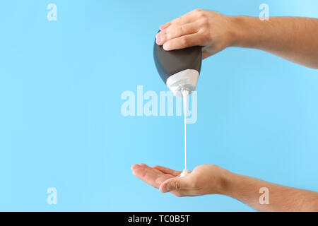 Mani maschio con bottiglia di shampoo sul colore di sfondo Foto Stock