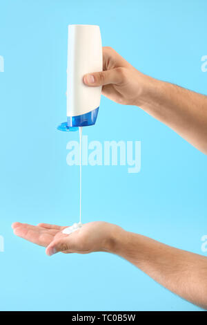 Mani maschio con bottiglia di shampoo sul colore di sfondo Foto Stock