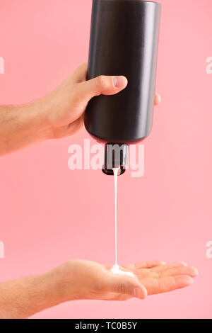 Mani maschio con bottiglia di shampoo sul colore di sfondo Foto Stock