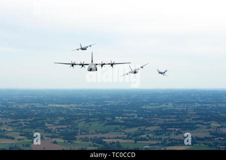 Tre C-130J Super Hercules, assegnato per la trentasettesima Airlift Squadron su Ramstein Air Base, Germania, volare come un C-17 Globemaster, assegnati alla riserva 446th ala sulla Royal Air Force Mildenhall, Inghilterra, sentieri un miglio dietro la formazione durante un volo di pratica vicino a Cherbourg, Francia, giugno 2, 2019. Il percorso intrapreso durante questa formazione pratica di volo è stato il percorso compiuto dalle loro rispettive unità' aeromobile legacy su DDay, Giugno 6, 1944. (U.S. Air Force foto di Senior Airman Kristof J. Rixmann) Foto Stock