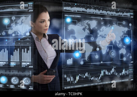 Young Lady funziona con virtual interfaccia grafica in ufficio futuristico Foto Stock
