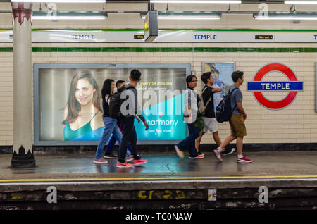 Un gruppo di giovani adulti a piedi lungo la piattaforma al Tempio della metropolitana di Londra. Foto Stock