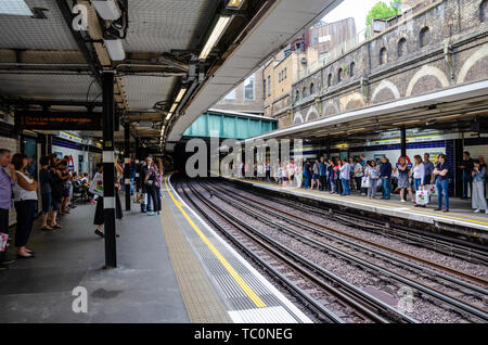 La gente in attesa sulle piattaforme a Sloane Square Stazione della metropolitana di Londra per un treno per arrivare. Foto Stock