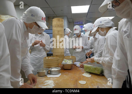 Il personale della cucina che indossa maschere igieniche prepara dietro il vetro Xiaolongbao un tipo di piccolo panino cinese al vapore (baozi) tradizionalmente preparato in uno xiaolong, un piccolo cestino di bambù fumante al ristorante cinese DIN Tai Fung Taiwanese a Taipei Taiwan Foto Stock