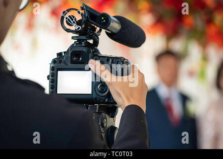 Videografo femmina nella parte posteriore sono shooing e registrazione video in caso di matrimonio. Foto Stock
