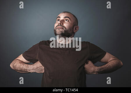 Ironico ritratto di uomo caucasico guardando verso l'alto e con le braccia sollevate e le mani sotto le ascelle. Orgogliosi e soddisfatti di guardare. Foto Stock