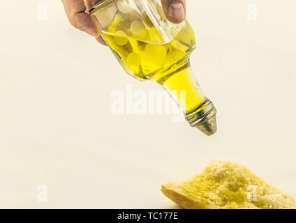 Close-up di olio d'oliva versando sulla fetta di pane su sfondo bianco, cibo sano Foto Stock