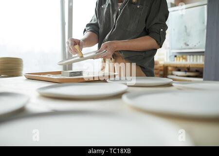 Metà secion ritratto di un irriconoscibile giovane donna carteggiatura a mano la coppa in ceramica nel laboratorio di ceramica, spazio di copia Foto Stock