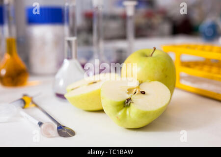 Mele fresche sulla tavola su sfondo di attrezzature di laboratorio e reagenti chimici. Concetto di ricerca della modificazione genetica del cibo Foto Stock