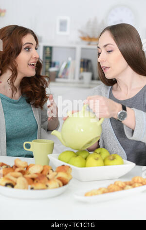 Ritratto di due femmina sorridente amici seduti al tavolo e bere il tè Foto Stock