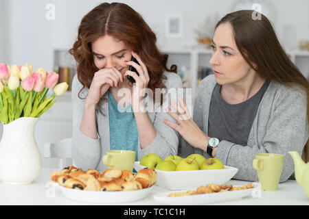 Ritratto di due amici di sesso femminile seduta a tavola e bere il tè Foto Stock