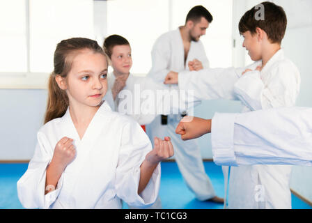 Gli adolescenti seri praticanti di karate nuovo si muove in coppie in classe Foto Stock