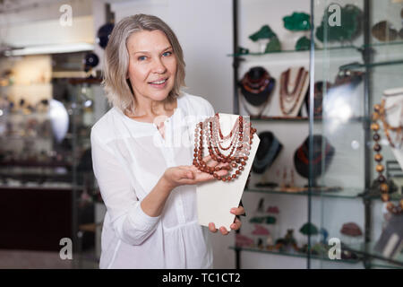 Venditore femmina dimostra di pietra dorata collana Foto Stock