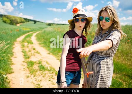 È la Madre che mostra a sorpresa la figlia cosa interessante durante il viaggio sulla strada del carrello, con fiori di papavero Foto Stock