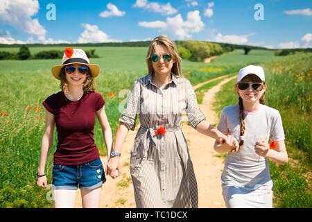 Madre e figlia di fiori di papavero sono a piedi sulla strada del carrello durante la primavera giornata di sole Foto Stock