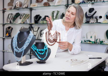 Venditore femmina dimostra di pietra dorata collana Foto Stock
