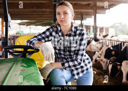 Giovani femmine trattore operatore lavorando su Dairy Farm Foto Stock