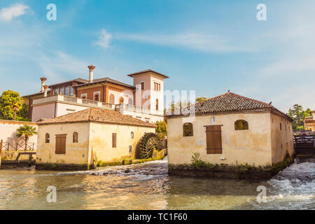 La città di Portogruaro in Veneto Italia con il fiume Lemene, torre e mulini Foto Stock
